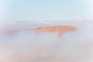 Abu Dhabi Prints: Top of a massive sand dune emerging from a thick cloud of fog after sunrise
