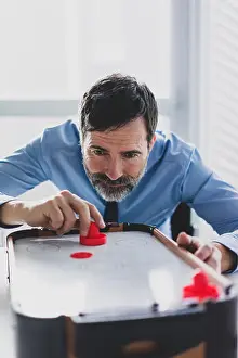 Distraction Prints: Mature businessman playing air hockey