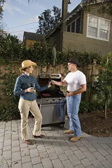 Caucasian Appearance Prints: Mature couple drinking beer next to barbeque grill