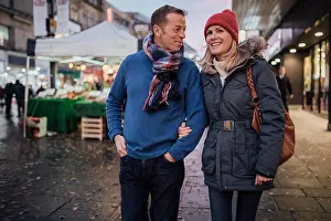 Beautiful People Prints: Mature coup;le are enjoying an evening stroll through the city christmas market