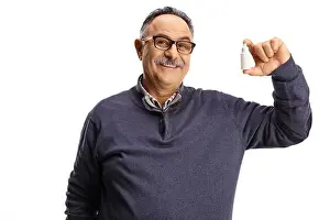 Eyesight Prints: Mature man holding a bottle of eye drops isolated on white background