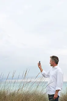 Forties Prints: Mature man photographing scenery with cell phone