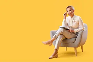 Trouble Prints: Mature psychologist with notebook sitting in armchair on yellow background