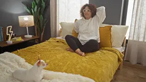 Homey Prints: A mature woman sits comfortably on a bed in a cozy bedroom