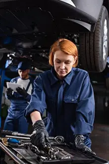 Repairman Prints: Mechanic in uniform taking tool near blurred african american colleague with digital tablet and car in garage