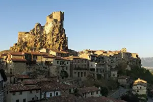 Medieval old town placed on rocky mountain with fortress on top in bright sunlight against blue sky
