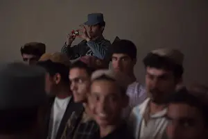 Donations Prints: A member of the Afghan Uniformed Police takes a photo of students waiting to receive donated books