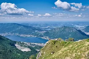 Motorboat Prints: Men walking on mountain peak with beautiful panorama in background of Lake Como - Piani d'Erna