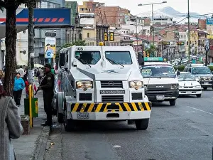 A Mercedes-Benz armored security truck transfers cash outside a bank in La Paz, Bolivia, while a guard stands by with a shotgun