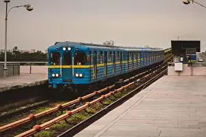 Exit Prints: A metro or underground train in blue and yellow color is approaching a metro station in Kiev