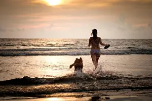 Best Friend Prints: Mexico, Nayarit, Young woman in bikini playing frisbee with her Golden Retriever dog at the beach