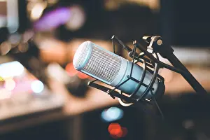 Speaker Prints: Microphone in a professional recording or radio studio, equipment in the blurry background
