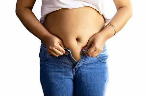 Middle Aged Prints: mid section of an indian woman with belly fat wearing blue jeans on white background