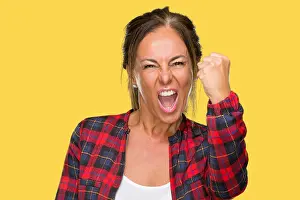 Punching Prints: Middle age adult woman wearing casual jacket over isolated background angry and mad raising fist frustrated