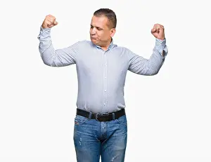 Muscles Prints: Middle age arab business man over isolated background showing arms muscles smiling proud