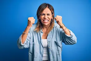 Fist Prints: Middle age beautiful woman wearing casual shirt standing over isolated blue background angry