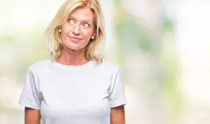 Stare Prints: Middle age blonde woman over isolated background smiling looking side and staring away thinking
