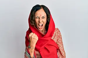 Saree Prints: Middle age hispanic woman wearing tradition sherwani saree clothes angry and mad raising fist frustrated