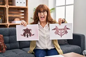 Middle Age Prints: Middle age hispanic woman working with rorschach test at psychology clinic angry and mad screaming frustrated