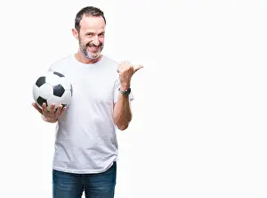 Optimistic Prints: Middle age hoary senior man holding soccer football ball over isolated background pointing