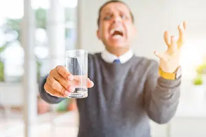 Pakistani Prints: Middle age man drinking glass of water at home very happy and excited
