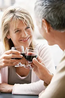 Face To Face Prints: Middle-aged couple sitting at outdoor cafe in Rome toasting wine glasses, close up