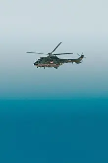 Directly Above Prints: Military helicopter aircraft flying search and rescue mission over a teal blue ocean