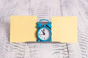 Scissors Prints: Mini blue colour alarm clock to show time placed in between two yellow notepapers