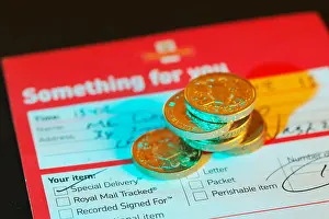 Missed delivery postage note from the UK Royal Mail with money in shot