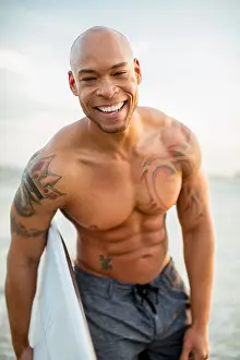 Three Quarter Prints: Mixed race man holding surfboard on beach