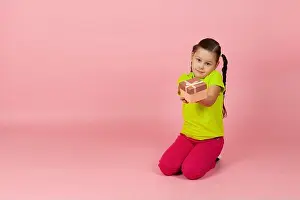 Valentines Day Prints: mock up girl with pigtails in a light green T-shirt and red pants hands us a gift box sitting on the floor