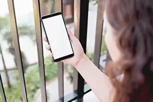 Mockup image of a woman using smart phone with blank white screen at home