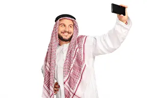 Veil Prints: Modern Arab taking a selfie with cell phone and smiling isolated on white background