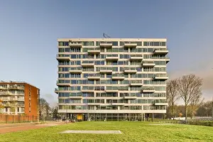 a modern building in the middle of a grassy area with trees and buildings on either side of the grass field