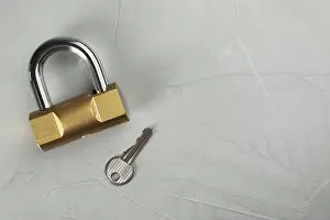 Safeguard Prints: Modern padlock with key on light grey table, flat lay. Space for text