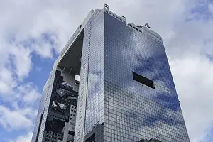 Reflecting Prints: A modern skyscraper with glass facade reflects the blue sky and white clouds, Osaka, Japan