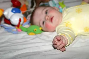 Awake Prints: Six month old baby girl in a yellow sleeper surrounded by her toys
