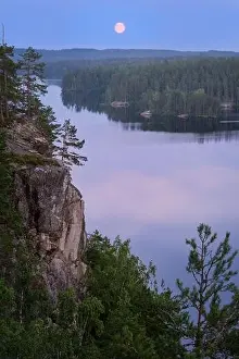Mood moonlight landscape with calm forest and lake at summer night in Finland