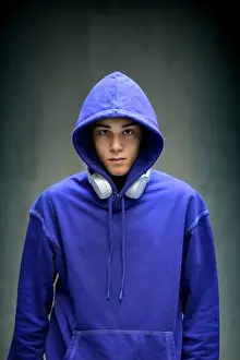Intense Prints: Moody serious teenage boy wearing a blue hoodie staring sullenly at the camera with earphones slung around his neck