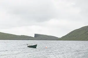 Morning view on lonely boat on cloudy Sorvagsvatn lake on cliffs of Vagar island, Faroe Islands, Denmark. Landscape photography