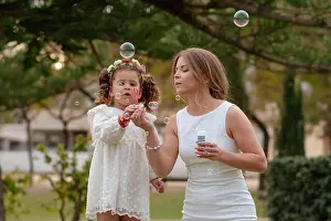 Offspring Prints: Mother and daughter blow soap bubbles outdoors