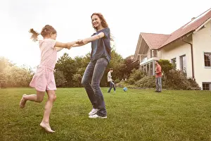 Barefoot Prints: Mother and daughter dancing in garden with family in background