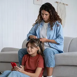 Childcare Prints: Mother making school hairstyle for beloved daughter at home. Childcare and parenting