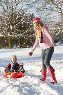 Pulling Prints: Mother Pulling Son On Sledge Through Snowy Landscape