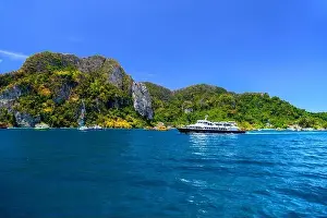 Krabi Prints: Motor ship in the bay of Ko Phi Phi Don Island with huge rocks and cliffs on a sunny day