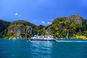 Krabi Prints: Motor ship in the bay of Ko Phi Phi Don Island with huge rocks and cliffs on a sunny day