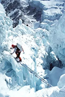 Vastness Prints: Mountain climber uses a ladder to cross a gorge in the Khumbu Icefall region on Mt Everest Two other climbers preceeded