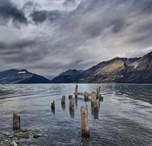 Mountain lake with remains of old wooden pier at windy cloudy morning