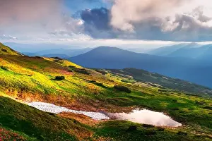 Mountain lake on sunrise time. Picturesque summer landscape with green mountain hills and sun rays in morning sky. Carpathian mountains