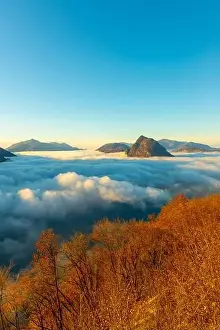 San Salvatore Prints: Mountain Peak San Salvatore Above Cloudscape with a Autumn Tree and Sunlight with Clear Sky in Lugano